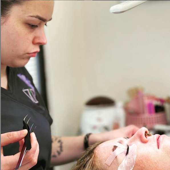 A beauty professional demonstrating techniques during eyelash extension classes at Vela Lash Bar