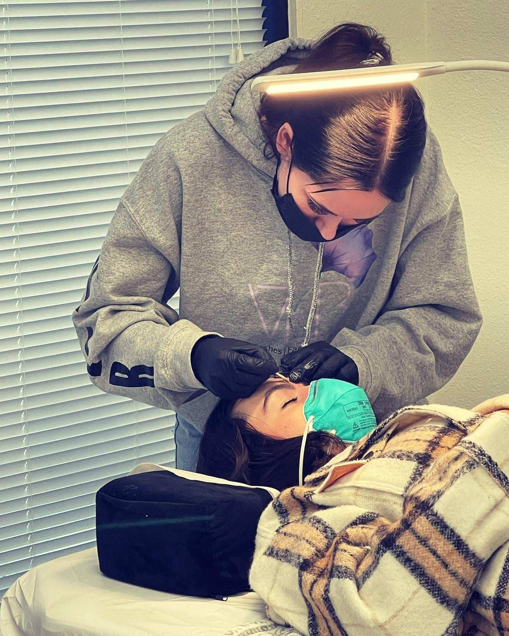 Instructor demonstrating lash lift and tint certification course techniques on a client in a training setting