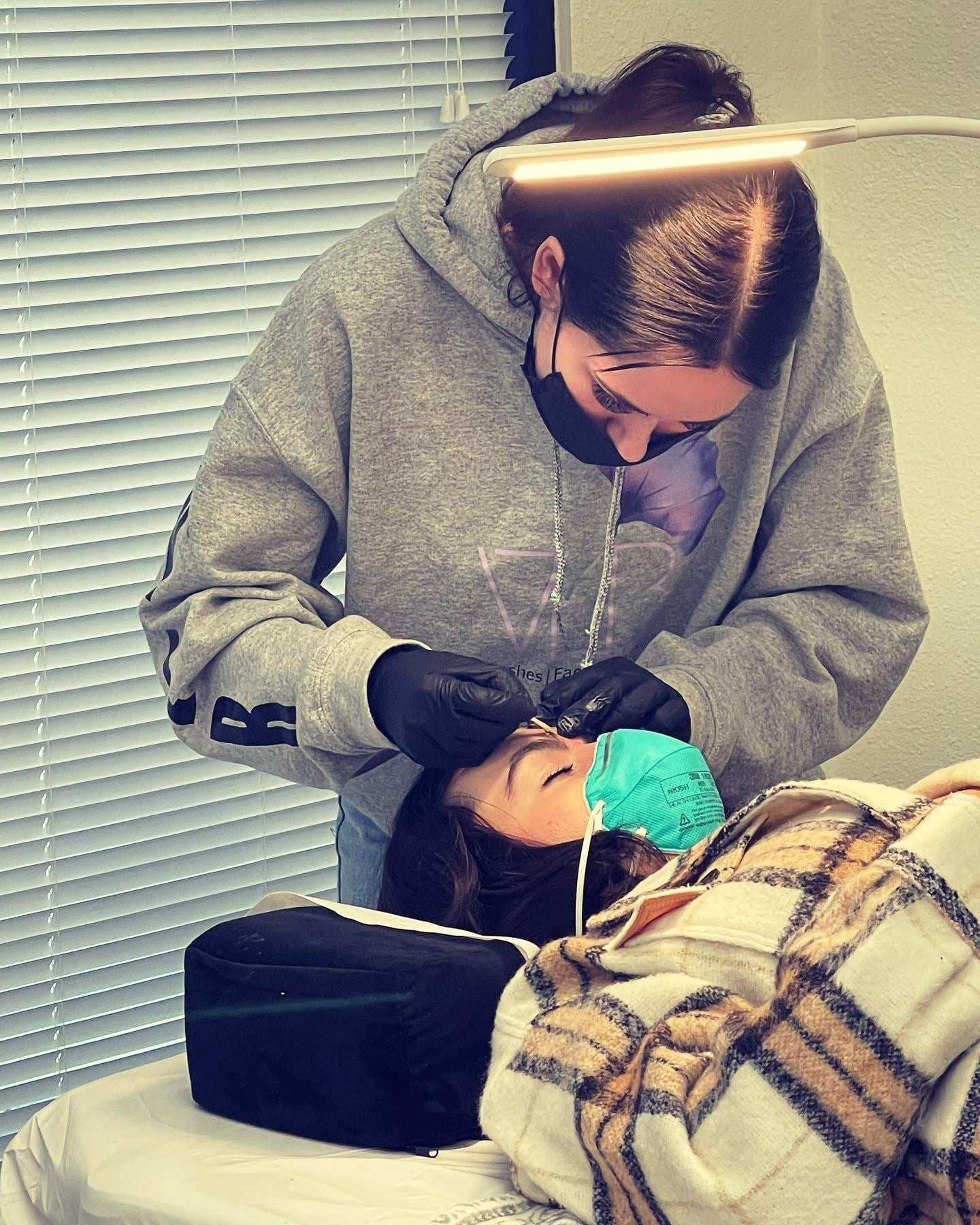 Instructor demonstrating lash lift and tint certification course techniques on a client in a training setting